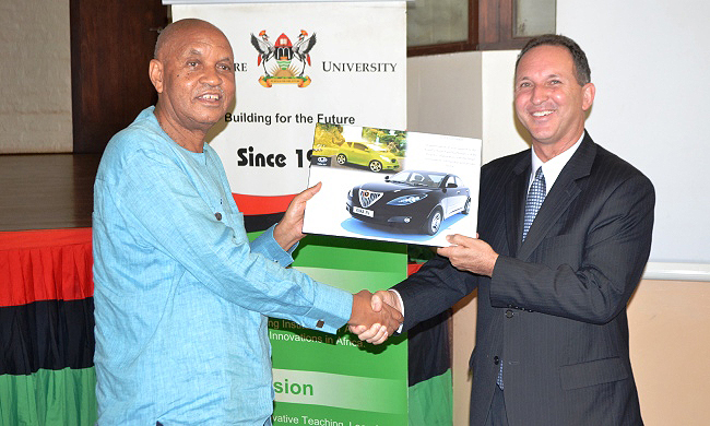 The Chancellor Prof. George Mondo Kagonyera (L) hands over a souvenir of the Kiira EV SMACK to outgoing Israel Ambassador H.E. Gil Haskel during his farewell visit to Makerere University, Kampala Uganda on 14th July 2014