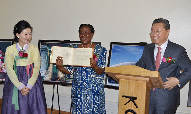 The University Librarian Prof. Maria Musoke (C) displays the historical Library Guest Book first signed by HRM Queen Elizabeth on 20th February 1959 after Korean Ambassador H.E. Park Jong Dae (R) appended his signature during the Official Korea Corner Opening, 6th August 2014, Makerere University, Kampala Uganda. Left is Mrs. Park, also in-charge of Cultural Affairs, Korean Embassy Kampala.