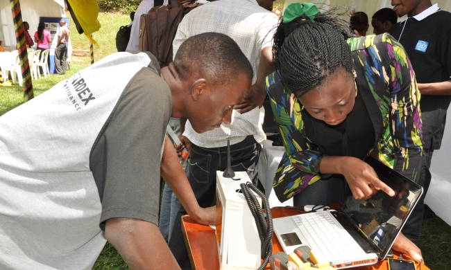 An exhibitor from the College of Engineering, Design, Art and Technology (CEDAT) explains the details of an innovation to a visitor during the Presidential Initiative Exhibition, 30th July 2013, Freedom Square, Makerere University, Kampala Uganda