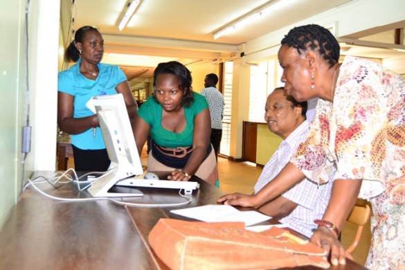 Dr Hellen Byamugisha (Extreme Left) looks on as Ms Eliz State demonstrates online access to Prof Apolo Nsibambi. Right is Prof. Maria Musoke.