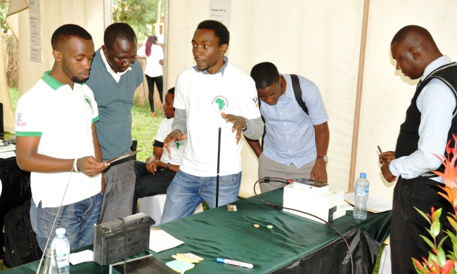 An exhibitor explains how the Radio in a Bucket works during the RIC4ACE Grants Call Launch, 13th August 2014, MakSPH, CHS, Makerere University, Kampala Uganda