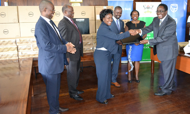 Mrs. Jackie Ayorekire receiving computers from Vice Chancellor Prof. John Ddumba-Ssentamu. Looking on is Ms Catherine Asinde (R), Mr.Thomas Tayebwa, Prof. Barnabas Nawangwe and Mr David Kahundha Muhwezi extreme right.