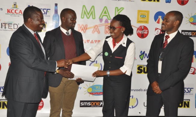Dean of Students-Mr Cyriaco Kabagambe (L) receives the return airticket prize from Brussels Airlines' Mrs. Belinda Sebunya and a colleague (R) as Guild President-H.E. Bala David witnesses, Mak Varsity Awards Media Brieifing, 23rd September 2015, Makerere University, Kampala Uganda