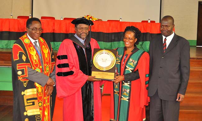 Prof. Joe Oloka Onyango (2nd Left) assisted by the Acting Principal, School of Law, Dr. Damalie Naggita Musoke (2nd Right) and flanked by the Vice Chancellor, Prof. John Ddumba-Ssentamu (Left) and DVCAA, Dr. Ernest Okello Ogwang (Right) shows off his plaque shortly after delivering his Inaugural Professorial Lecture-GHOSTS AND THE LAW, 12th November 2015, Makerere University, Kampala Uganda