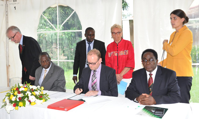 The Swedish Ambassador to Uganda (Seated middle) signing the agreement on his right is Hon. Matia Kasaija, Minister of Finance, Planning and Economic Development and Makerere University Vice Chancellor  Prof. John Ddumba-Ssentamu on his left. Standing behind (in red jacket) is Dr. Katri Pohjolainen, First Secretary Research Cooperation