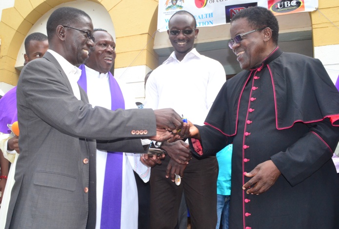 The Chaplain, Rev. Josephat Ddungu together with the Chairperson of the St. Augustine Catholic Community Prof. Edward K. Kirumira hands over the car keys to Monsignor (Msgr.) Dr. Lawrence Kanyike.