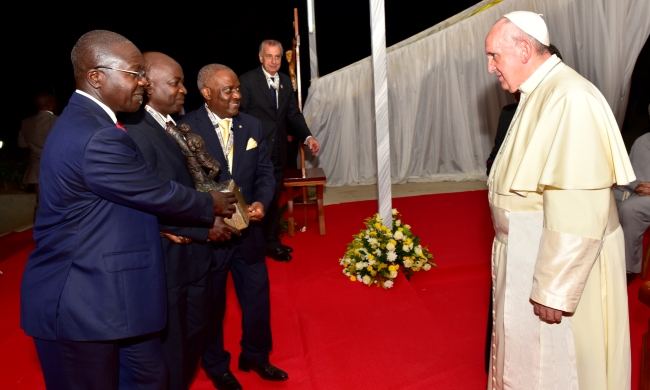 Prof. George Kyeyune-MTSIFA, CEDAT (2nd L) assisted by City Businessman-Mr. Yiga (L) and Rtn. Emmanuel Katongole-Quality Chemicals (3rd L) prepares to present a Bust of Uganda Martyr Anderea Kaggwa to Pope Francis during his visit to Munyonyo Shrine, Kampala Uganda on 27th November 2015