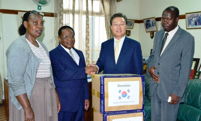 The South Korean Ambassador to Uganda H.E. Park Jong Dae (2nd R) hands over the Book Donation to the Chancellor, Prof. Ezra Suruma (2nd L) as The DVCAA-Assoc. Prof. Ernest Okello Ogwang (R) and Acting University Librarian-Dr. Hellen Byamugisha (L) witness on 31st March 2016, Makerere University, Kampala Uganda