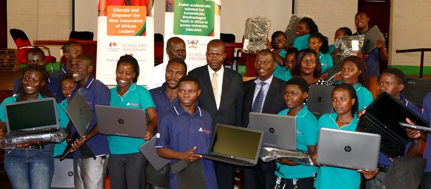 Some of the Scholars who received laptops posing for a photo with the Chairperson of the MCF Steering Committee, Dr. Ernest Okello Ogwang, Dean of Students Mr. Cyriaco Kabagambe, Monitoring, Evaluation and Learning Coordinator Mr. Tito Okumu and the Project Manager Ms. Okumu Jolly.