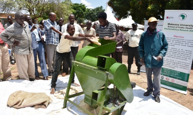 RAN's Steven Ssekanyo demonstrates his ‘Kungula’ Maize Thresher with a winnowing fan to farmers during the Knowledge Transfer Activity in Pallisa District, Uganda