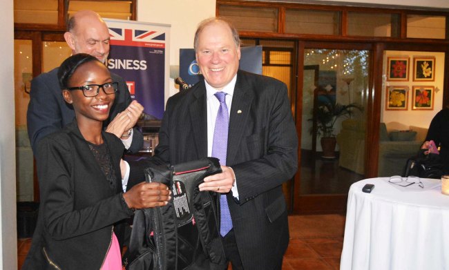 CEDAT Student-Tracy Tusiime (L) receives her internship award from a CB&I Official as British High Commissioner to Uganda-H.E. Peter West (rear) applauds, 27th June 2017, Nakasero, Kampala Uganda