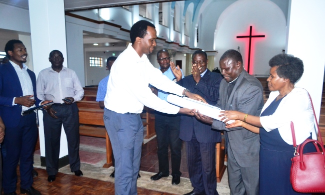 Project Manager-Mr. Jesse Tukacungurwa (C) hands over the architectural designs to St. Francis Chaplain-Rev. Canon Amos Turyahabwe (2nd R) as Dean of Students-Mr. Cyriaco Kabagambe (3rd R) and Director Estates and Works-Eng. Fred Nuwagaba applaud during the ceremony on 8th June 2017, St. Francis Chapel, Makerere University, Kampala Uganda
