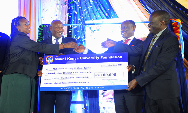 MKU Vice Chancellor Prof, Stanley Waudo {right} and Makere UniversitySeptember. 19, 2017 Vice chancellor Prof. Barnabas Nawangwe { second right }  Receive a cheque  of 10million Kenyan  shilling from MKU member   Board of Directors Jane Nyutu {left} and MKU Vice Chairman Dr.Vincent  Gaitho, during  the launch of MKU and Makerere university's MoU signing at Thika  Main Campus on September. 19, 2017