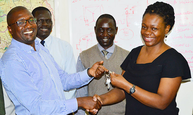 Outgoing EWD Director-Eng. Fred Nuwagaba (L) hands over office keys to Eng. Christina Kakeeto (R) as Mr. Patrick Akonyet (2nd L) and a member of the EWD staff witness during the ceremony, 30th November 2017, Makerere University, Kampala Uganda