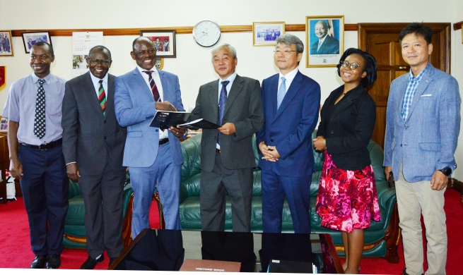 Prof. Barnabas Nawangwe (3rd L) exchanges the signed JVA with Mr. Peter Moon (C) as L-R: Mr. Gordon Murangira, Prof. Bernard Bashaasha, Mr. Joseph Moon, Mrs. Lillian Helen Kuteesa and Mr. James Lee witness after the signing ceremony, 22nd December 2017, Makerere University, Kampala Uganda. Under the Agreement, MAP will set up a modern pig farming and processing facility at MUARIK, Kabanyolo.