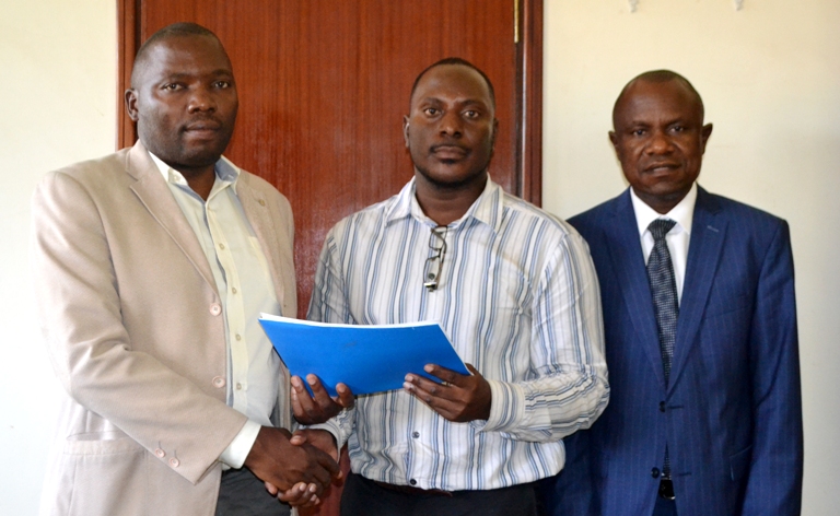Eng. Frank Kitumba handing over office to Mr. Mugabi Samuel Paul. Right, is the Acting Deputy Vice Chancellor for Finance and Administration Dr. Eria Hisali.