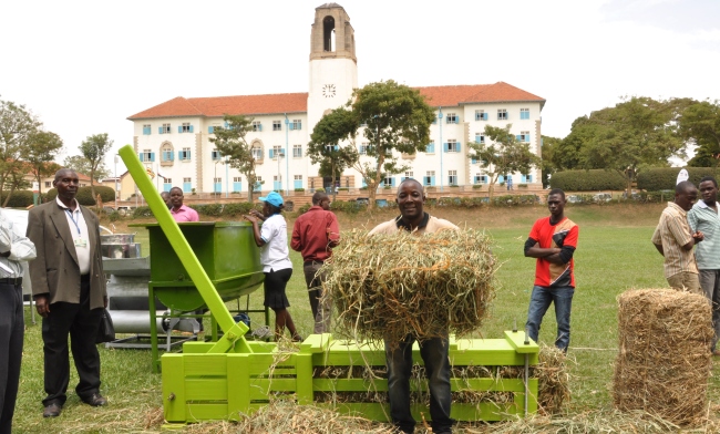 An AFRISA student demonstrates hay baling during the Presidential Initiative for Science and Technology exhibition, 31st July 2014, Freedom Square, Makerere University, Kampala Uganda
