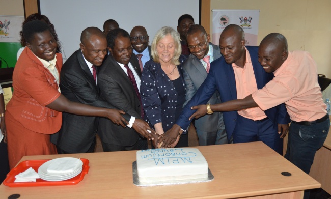 Ms. Christina Malmberg Calvo (C) flanked by DVCFA-Prof. William Bazeyo (3rd L), Assoc. Prof. Eria HIsali (2nd L), Assoc. Prof. Umar Kakumba (3rd R), Eng. Usama Kayima (2nd L), DBSA's Dr. Dumisani Magadlela (Rear) and other members of the MPIM Board cut the cake marking the Consortium's lanch, 22nd June 2018, CoBAMS, Makerere University, Kampala Uganda