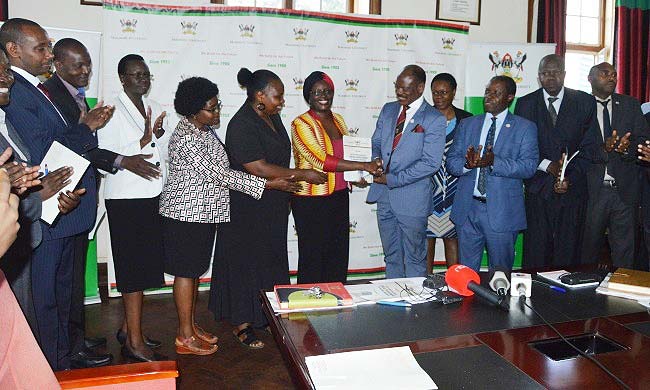 The Chairperson-Prof. Sylvia Tamale flanked by members of the Committee Investigating Sexual Harassment (Left) hands over the report to Vice Chancellor-Prof. Barnabas Nawangwe, flanked by Members of Management (Right) on 25th June 2018, Makerere University, Kampala Uganda