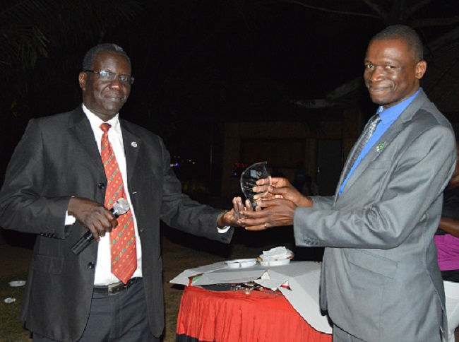 Mr.  Augustine Tamale receiving a plaque as a sign of appreciation for the unmeasurable service he rendered to the University. The Plaque was handed over to him by the Director of Internal Audit Mr. Walter Yorac Nono on behalf of Makerere University.