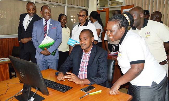 Hon. Frank Tumwebaze-Minister of ICT & National Guidance (Seated) launching the Technology and Innovations Support Centre during World Library Day celebrations on 13th July 2018. Looking on is the Vice Chancellor Prof. Barnabas Nawangwe (2nd L), Dr. Joseph Muvawala-Executive Director National Planning Authority (L), University Librarian-Dr. Helen Byamugisha (3rd R) and Ms Rhoda Nalubega-Head Africana Section (Right), Main Library, Makerere University, Kampala Uganda.