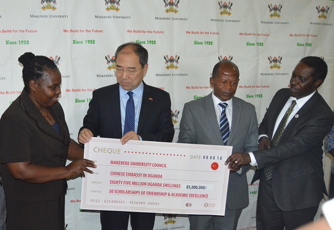 The Ambassador of China to Uganda, H.E. Zheng Zhuqiang, handing over the cheque to  the Deputy Vice Chancellor for Finance and Administration Prof. William Bazeyo. Present were the State Minister for Higher Education Hon. John Chrysostom Muyingo and  the Acting Director of Gender Mainstreaming, Dr. Euzobia M. Baine.