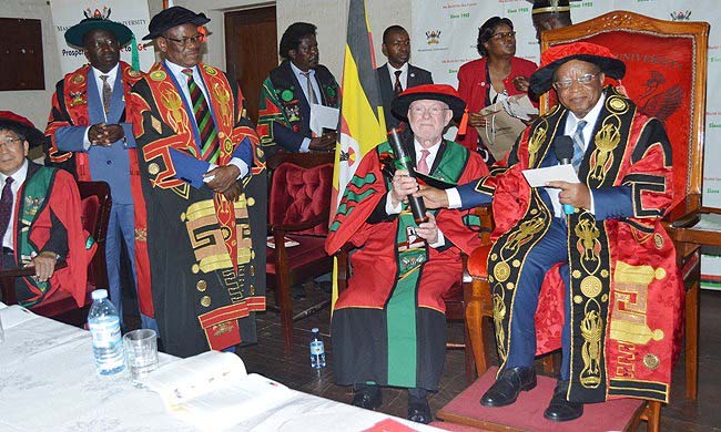 Dr. David Poplack, Professor of Pediatrics at Baylor College of Medicine receives his award from the Chancellor, Prof. Ezra Suruma (Right) at a special graduation ceremony held on 9th August 2018 in the Main Hall. Looking on is the Vice Chancellor Prof Barnabas Nawangwe (Standing 2nd L) and Principal College of Health Sciences - Prof. Charles Ibingira (Standing L)