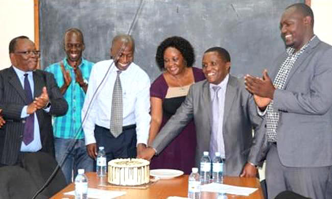 The Dean MakSPH-Assoc. Prof. Rhoda Wanyenze (3rd R) joins Assoc. Prof. Nazarius Mbona Tumwesigye (2nd R) and Assoc. Prof. Noah Kiwanuka (3rd L) to cut the cake as Prof. Fred Wabwire-Mangen (L), Mr. Abraham Matovu (2nd L) and Mr. Dembe Amos Ashaba (R) applaud during the handover ceremony on 14th September 2018, MakSPH, College of Health Sciences, Makerere University, Kampala Uganda