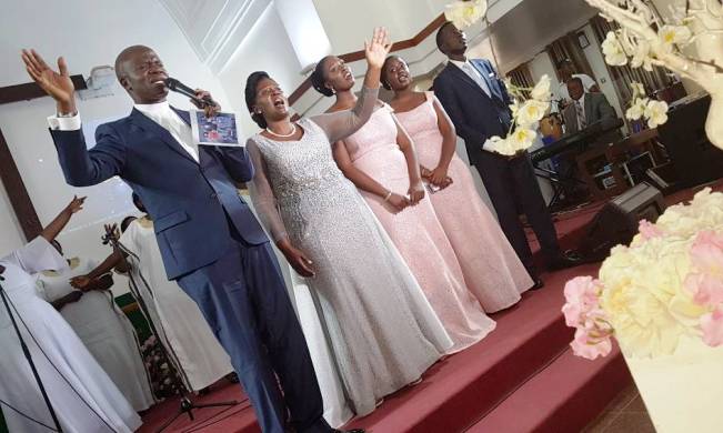 L-R: St. Francis Chaplain-Rev. Onesimus Asiimwe, his wife-Mrs. Florence Asiimwe and children Marjorie Kiconco, Ruth Ariho and Daudi Mwesigwa sing hallelujah during the Silver Jubilee Anniversary Service on Saturday, 22nd September 2018, St. Francis Chapel, Makerere University, Kampala Uganda