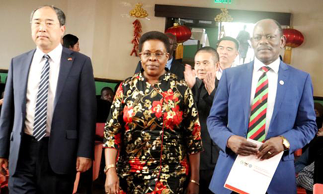 L-R: Chinese Ambassador to Uganda-H.E. Zheng ZhuQiang, Minister for KCCA-Hon. Beti Olive Kamya and the Vice Chancellor-Prof. Barnabas Nawangwe make their way into the Main Hall for the Confucius Institute 4th Anniversary Celebrations as Outgoing Director-Prof. Hong Yonghong (Rear) applauds, 9th November 2018, Makerere University, Kampala Uganda