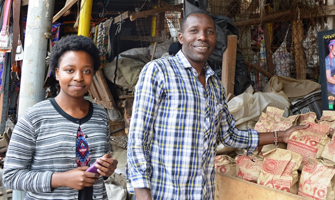 Yvonne (BrightGreen's intern) and Moses (BrightGreen's delivery man), helping set up the display shelf for Rosemary, one of BrightGreen's distributors. Image:Erika Desmond, MIT D-Lab