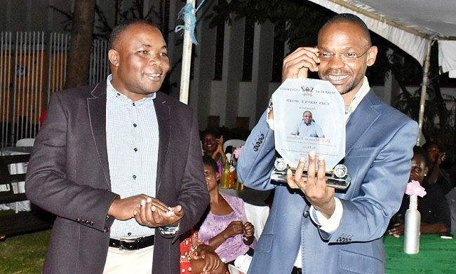 The DVCAA-Dr. Umar Kakumba (R) reads the words on Prof. Mnason Tweheyo's plaque shortly before handing it over to him at the CAES End of Year Party on 14th December 2018, Forestry Gardens, SFEGS, CAES, Makerere University, Kampala Uganda