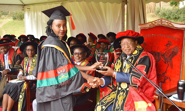 The Chancellor, Prof. Ezra Suruma (Right) hands over the ACCA Uganda Award to Ms. Tumukunde Elizabeth, the best performing student in Bachelor of Commerce (Accounting Option) during the 2nd Session of the 69th Graduation Ceremony at Makerere University, Kampala Uganda