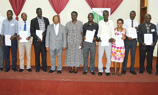 Some of the participants posing for a photo with the Chancellor, Prof. Ezra Suruma (4th L) and the Director for Education Standards in the Ministry of Education and Sports, Dr. Kedress Turyagyenda (5th L) after recieving their certificates on Friday 11th January 2019 at Makerere University, Kampala Uganda