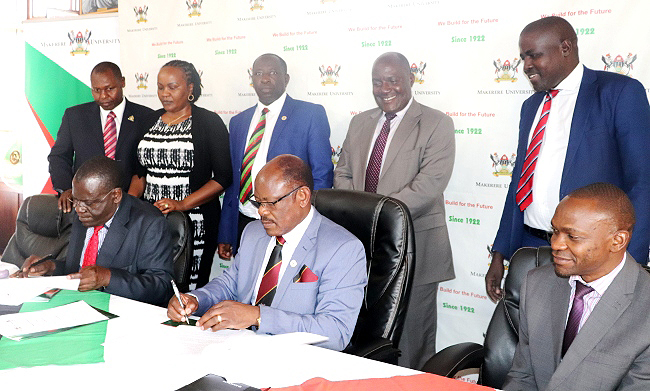 Seated: Prof. Stanley Waudo (L) and Prof. Barnabas Nawangwe (C) sign the MoU while DVCAA-Dr. Umar Kakumba (R) and Standing L-R: Prof. Mwangi Peter Wanderi, Dr. Bibianne Waiganjo, Prof. Charles Ibingira, Prof. Fred Masagazi Masaazi and Mr. Henry Mwebe witness on 14th January 2019, Makerere University, Kampala Uganda