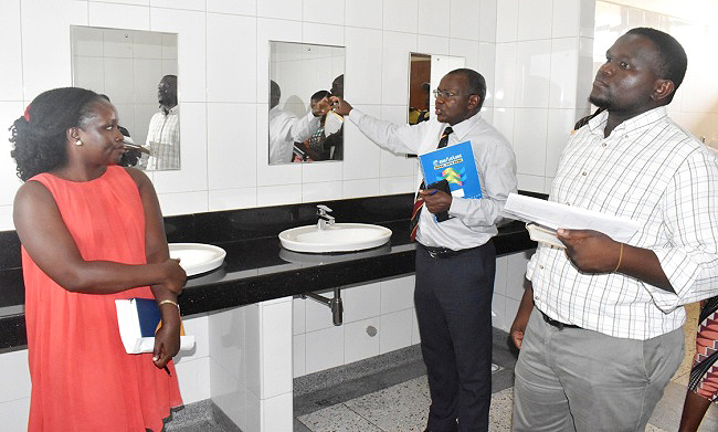 The Principal CAES-Prof. Bernard Bashaasha (C) flanked by Arch Designs Ltd. representatives Eng. Florence Lunyoro (L) and Arch. Dickson Wetala (R) inspects one of the Washrooms in the Gradute Training and Research Lab on 11th Feburary 2019 during the site handover at MUARIK, Makerere University, Wakiso Uganda