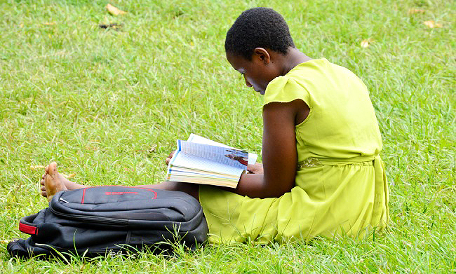A female student relaxes in the greens during a break between her lectures, Makerere University, Kampala Uganda