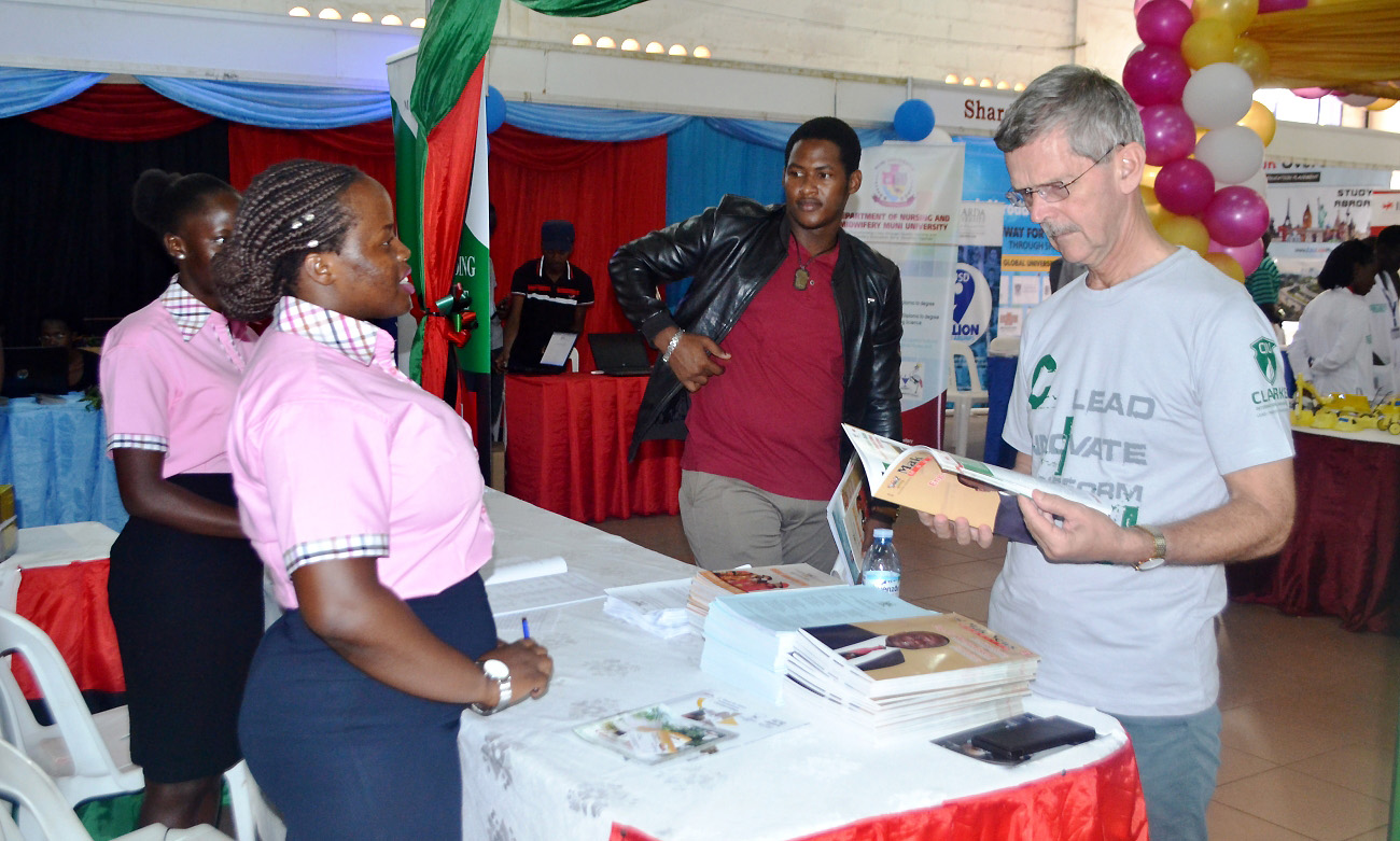 Dr. Ian Clarke (Right) flips through a copy of the Mak News Magazine during his visit to the Makerere University Stall at the 11th NCHE Higher Education Exhibition, 21st March 2019, UMA Exhibition Hall, Lugogo Showgrounds, Kampala Uganda. 2nd Left is ariticle author Ms. Proscovia Nabatte