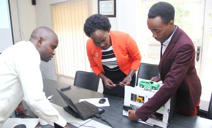 Evarest Ampaire shows off a prototype of his innovation the Automatic Car Parking System, to RAN’s Communications Manager-Harriet Adong (Centre) and another panellist during Pitch Tuesday on 22nd January 2019, ResilientAfrica Network (RAN) Offices, Plot 30, Upper Kololo Terrace, Kampala, Uganda