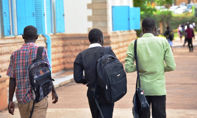Male students walk past the Main Building, Makerere University, Kampala Uganda