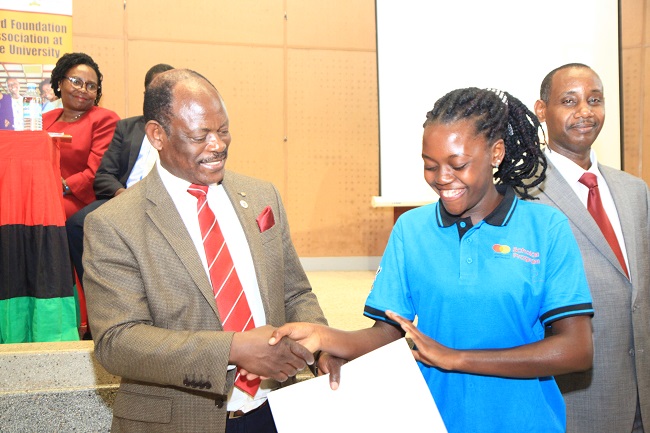 A student recieving the Scholarship Award letter from the Vice Chancellor Prof. Barnabas Nawangwe. On right, is Prof. Aaron Mushengyezi; theChairperson of Selection Committee.