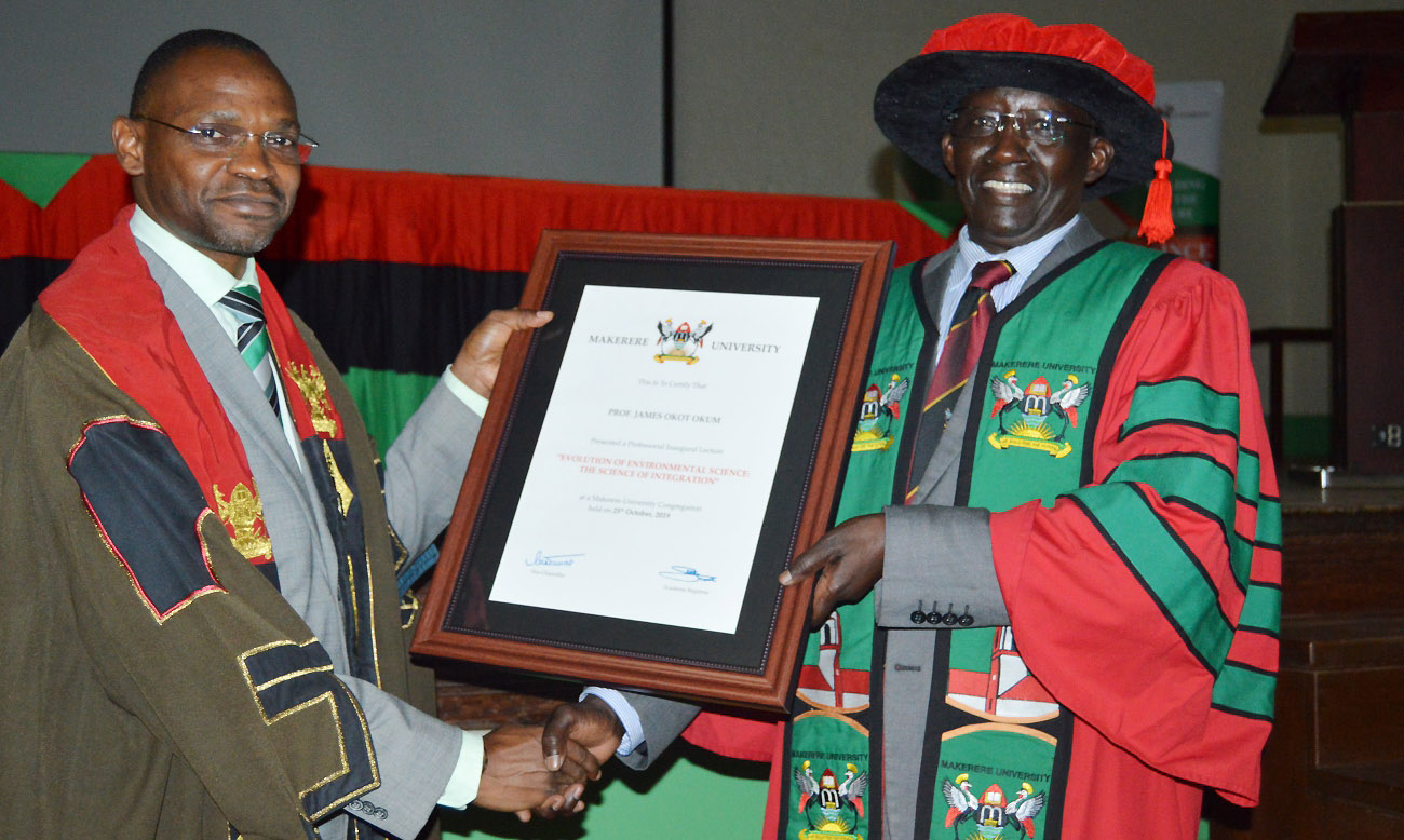 The Acting Vice Chancellor and DVCAA-Dr. Umar Kakumba (Left) presents a framed certificate to a beaming Prof. James Okot-Okumu (Right) following the successful delivery of his Professorial Inaugural Lecture on 25th October 2019, Main Hall, Makerere University, Kampala Uganda