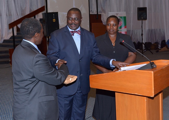 The Acting Deputy Vice Chancellor (Finance and Administration), Prof. William Bazeyo receiving the Minister's contribution from the Deputy Speaker of Parliament, Rt. Hon. Jacob  Oulanyah. on right, is the Director, Gender Mainstreaming Directorate, Dr. Euzobia Mugisha Baine.
