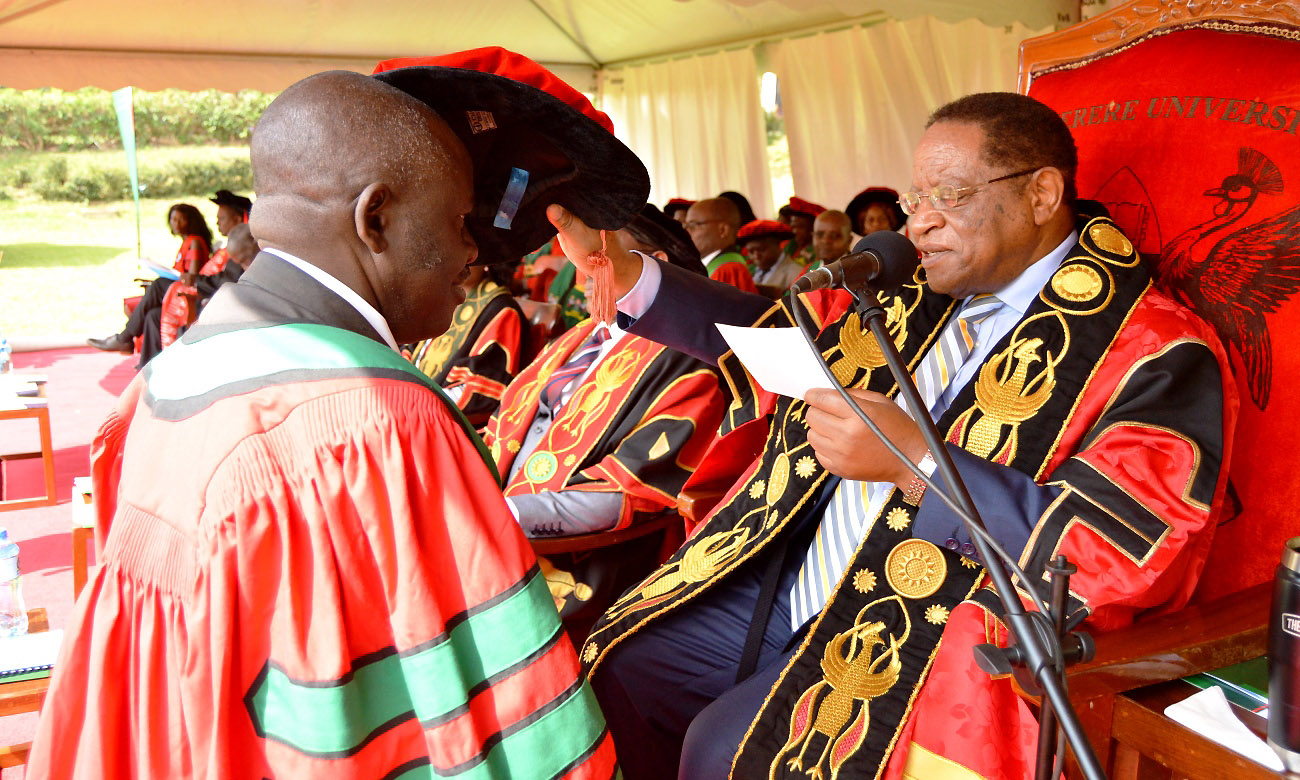 The Chancellor-Prof. Ezra Suruma (Right) confers a PhD upon a male Graduand (Left) during Day 2 of the 69th Graduation Ceremony on 16th January 2019, Freedom Square, Makerere University, Kampala Uganda.