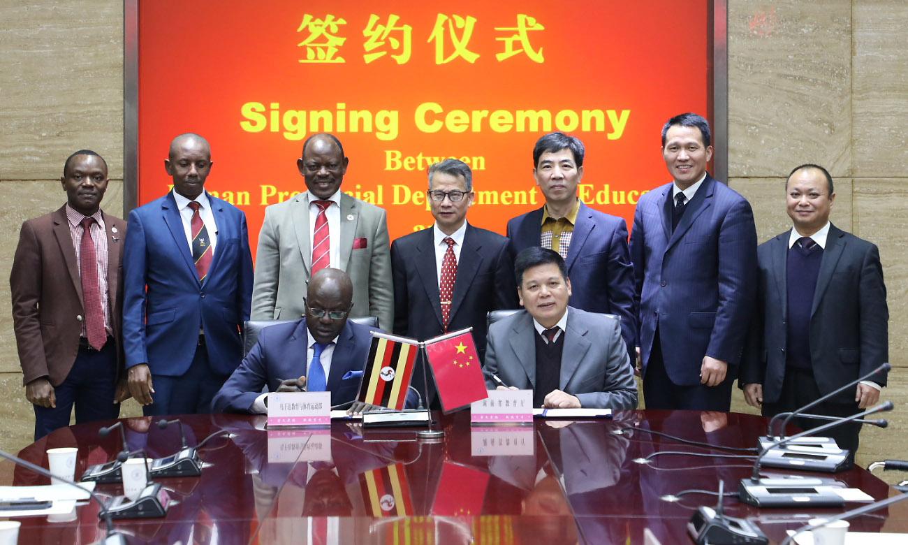 Standing: The Vice Chancellor-Prof. Barnabas Nawangwe (3rd Left), Dr. Gilbert Gomoshabe (2nd Left), Mr. Mathias Ssemanda (Left) and other officials witness as Seated: The Permanent Secretary, MoES-Mr. Alex Kakooza (Left) and the Deputy Director, Hunan Provincial Department of Education sign the MoU on 11th December 2019 in China.