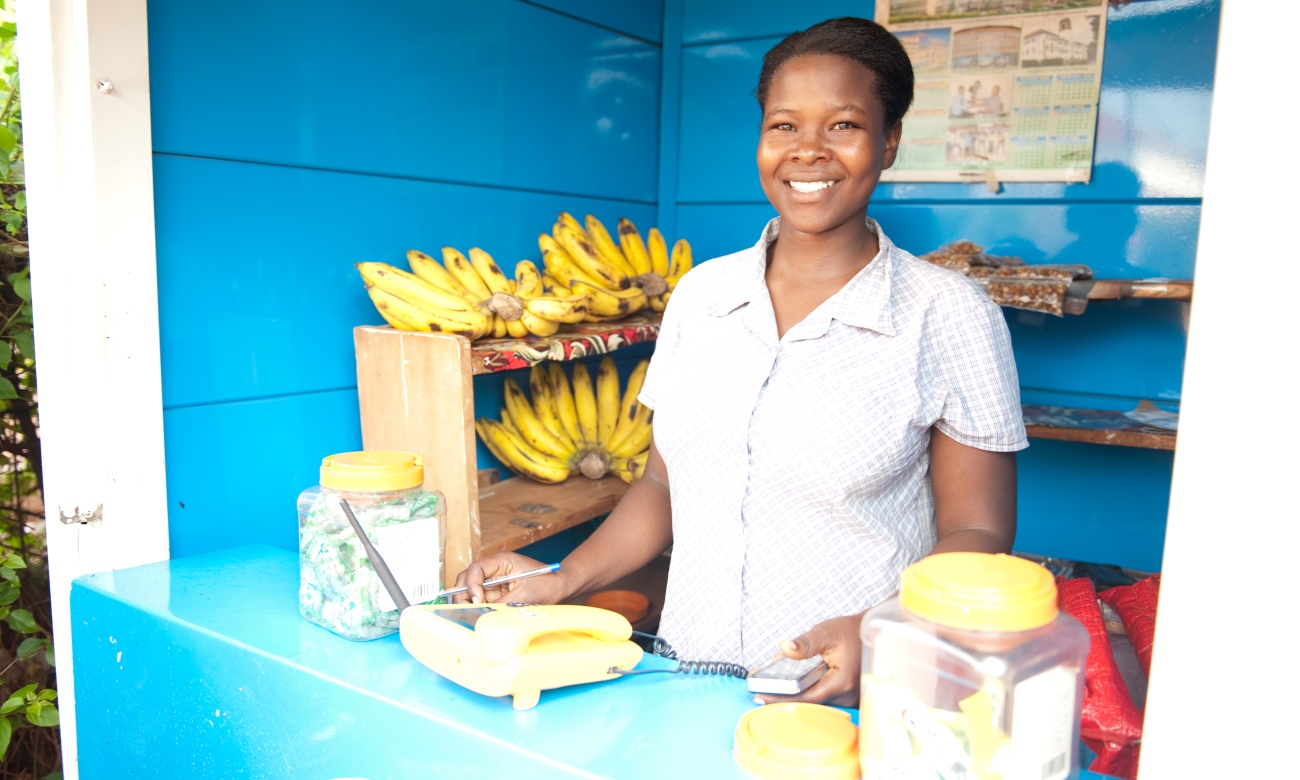 A female attendant in a kiosk smiles for the camera. Date taken: 12th August 2020. Makerere University research shows that at 38%, economic factors are the most frequent cause of high fertility in Kabale District.