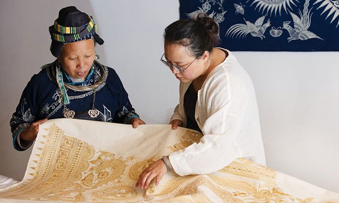 Xiao Liu, right, a community organizer with Roots Studio, looks over a print with an artist from Guizhou, China. Photo: 心奕