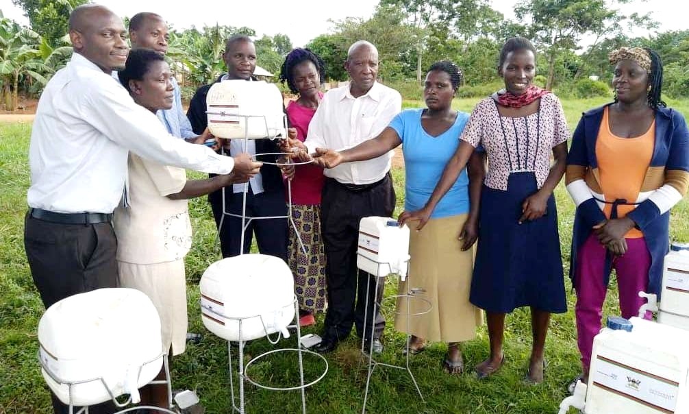 Teachers at Bishop Kauma Zzinga Primary School receiving hand washing facilities from Dr. David Musoke (Left) and Mr. Stanley Kabuye-LC III Chairperson, Bussi sub-County, Wakiso District (Centre with white shirt) in March 2020.