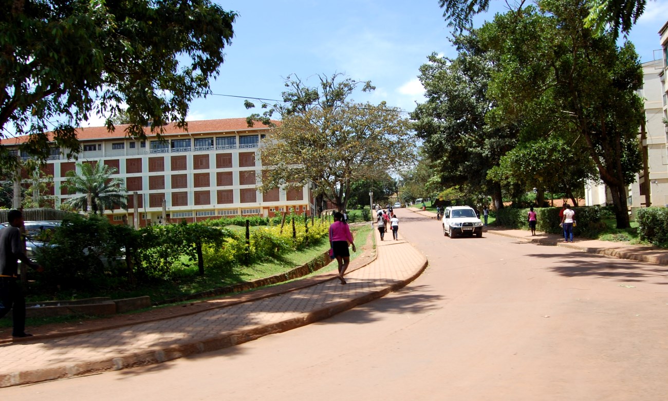 Pedestrians walk up Northcote Road with the Main University Library to the left and Quarry Road Flats to the right, Makerere University, Kampala Uganda.