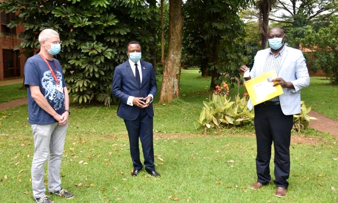 The Ambassador of France to Uganda—H.E. Jules-Armand Aniambossou (Centre) and another official listen to Dr. Misaki Wayengera (Right) talk about the consignement of peptides received from France on 4th June 2020, Kampala Uganda.